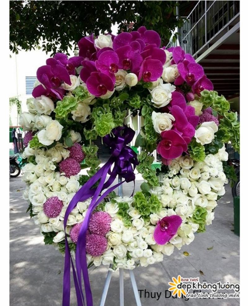 Một thợ cắm hoa chuyên nghiệp đang chuẩn bị một kệ hoa làm biểu tượng chia buồn đám tang tại cửa hàng